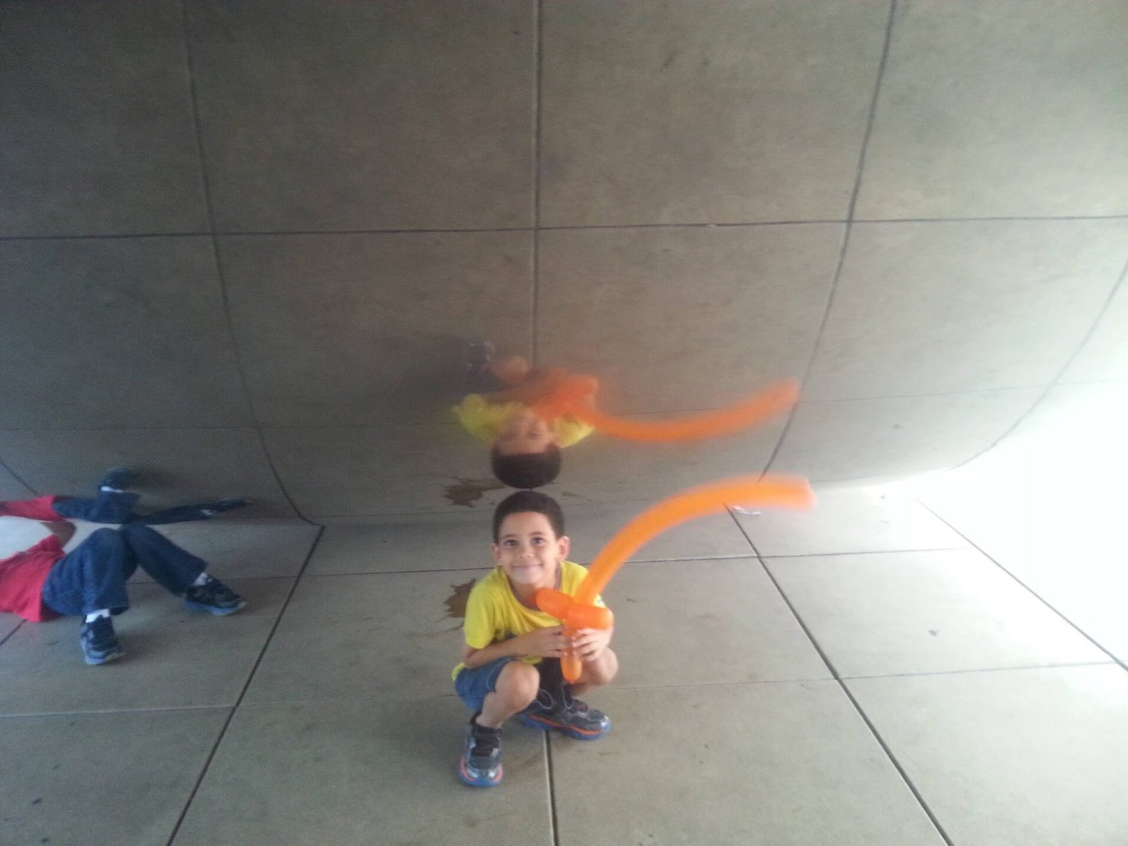 boy and his reflection in the cloud gate in chicago