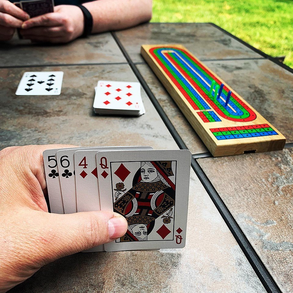 cribbage board with cards in hand and another player