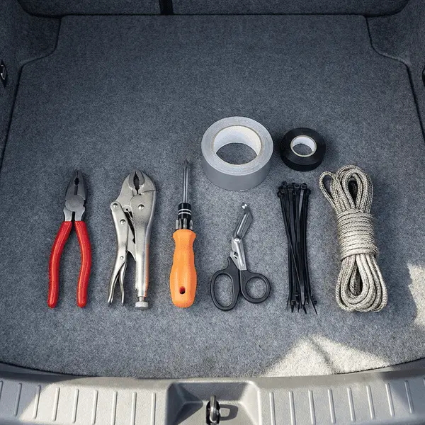 Basic car emergency tools laid out neatly including pliers vise grips screwdriver scissors duct tape zip ties and rope