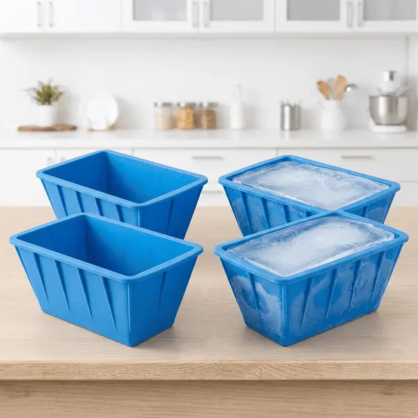 Four blue silicone ice molds on a kitchen counter, two empty and two filled with large frozen ice blocks for road trip cooler prep