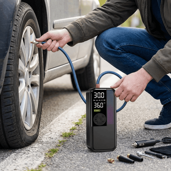 Person using a portable tire inflator to air up a low tire on the side of the road