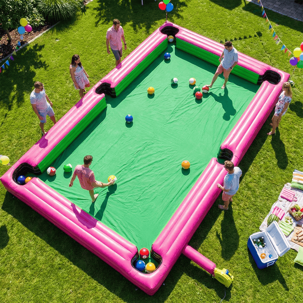 Giant inflatable human billiards pool table on a sunny backyard lawn with adults playing