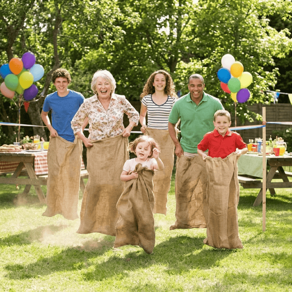 Potato sack race at a family reunion with adults and kids hopping and laughing on a sunny lawn