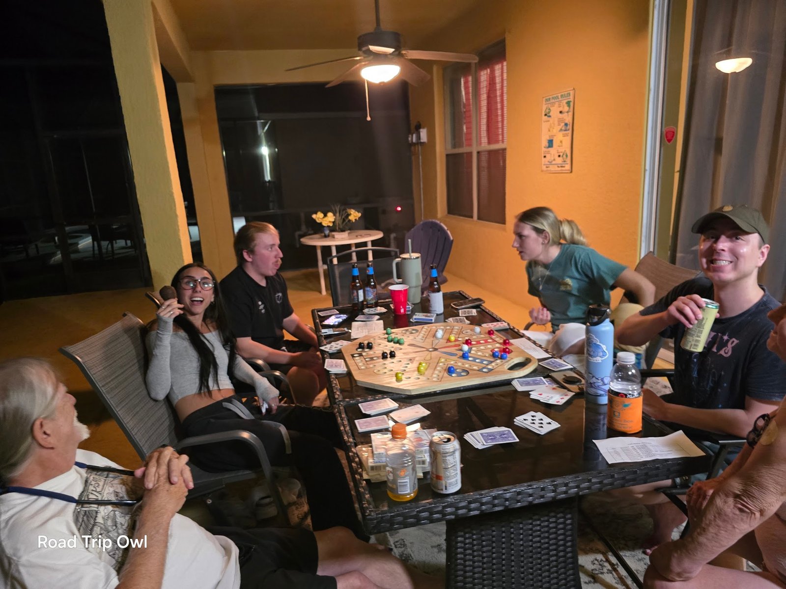 Family game night on the patio at a Florida vacation rental — multiple generations playing Aggravation around the table on a warm Florida evening.
