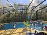 A family playing pool volleyball in a screened Florida vacation rental — the kind of easy, unstructured family time that makes a first vacation feel like a success.