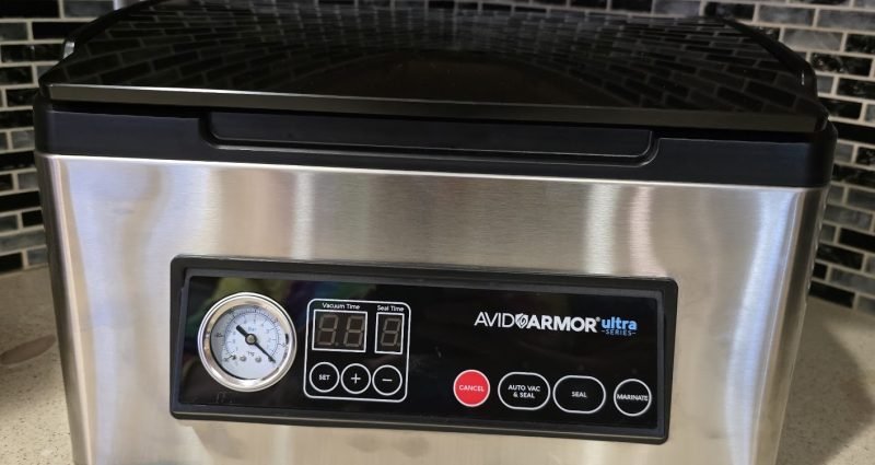 Avid Armor USV32 chamber vacuum sealer on kitchen counter showing control panel and pressure gauge