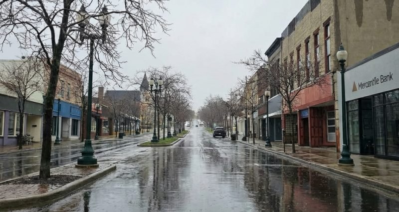 Rainy day on a downtown street in Petoskey, Michigan with wet pavement and reflections